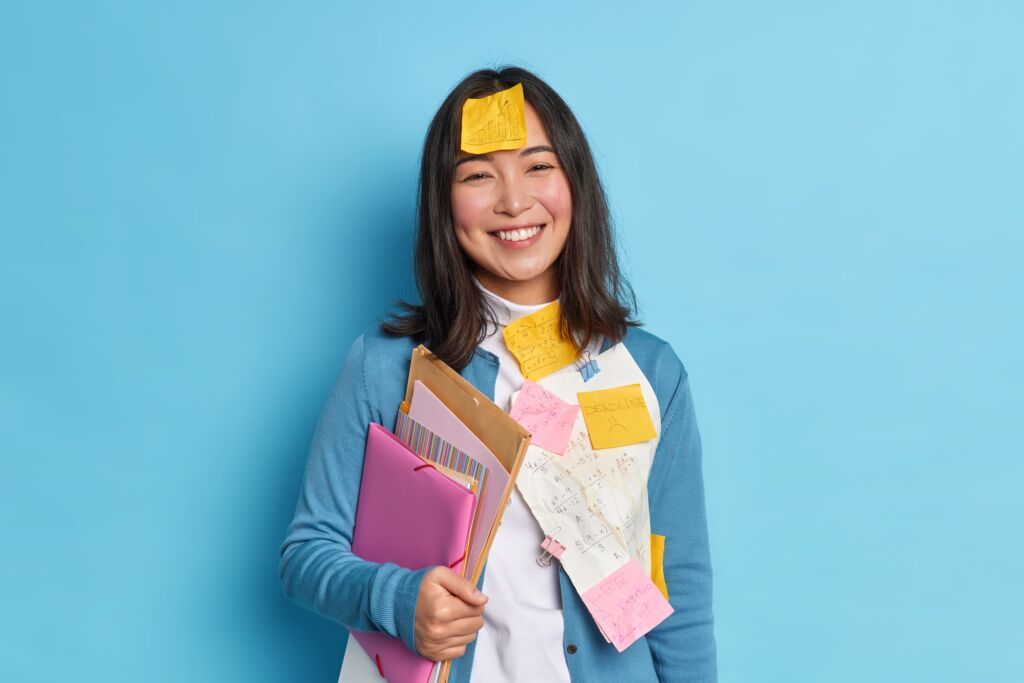 smiling asian teacher with post it notes on her body